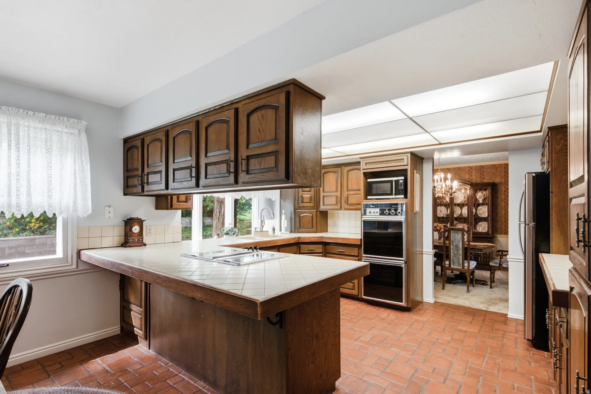 Kitchen featuring a large window, tile flooring, wood cabinetry, built-in double oven, and integrated microwave