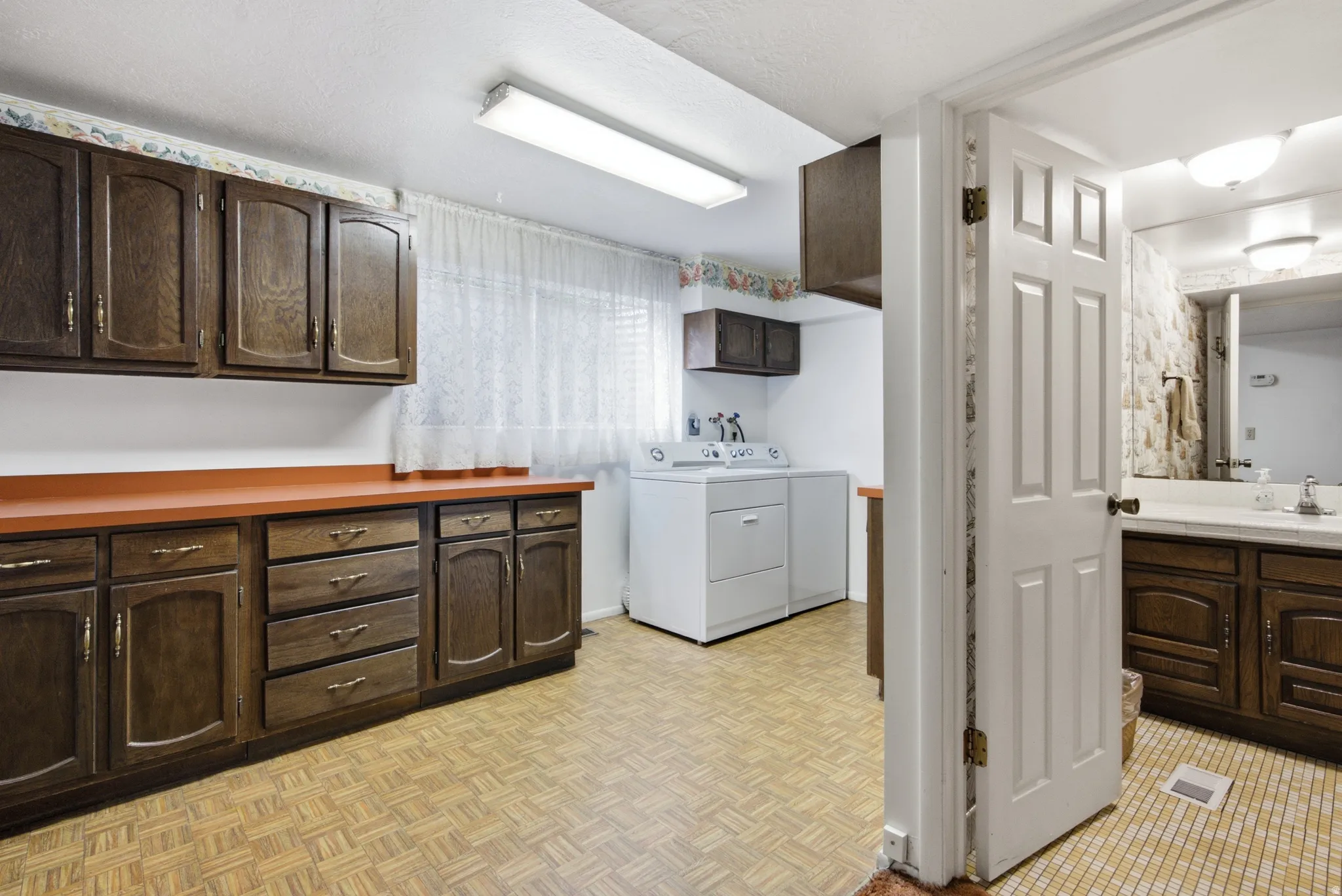 Dedicated laundry area featuring a washer and dryer appliance hookup, extensive wood-finish cabinetry, and laminate countertops