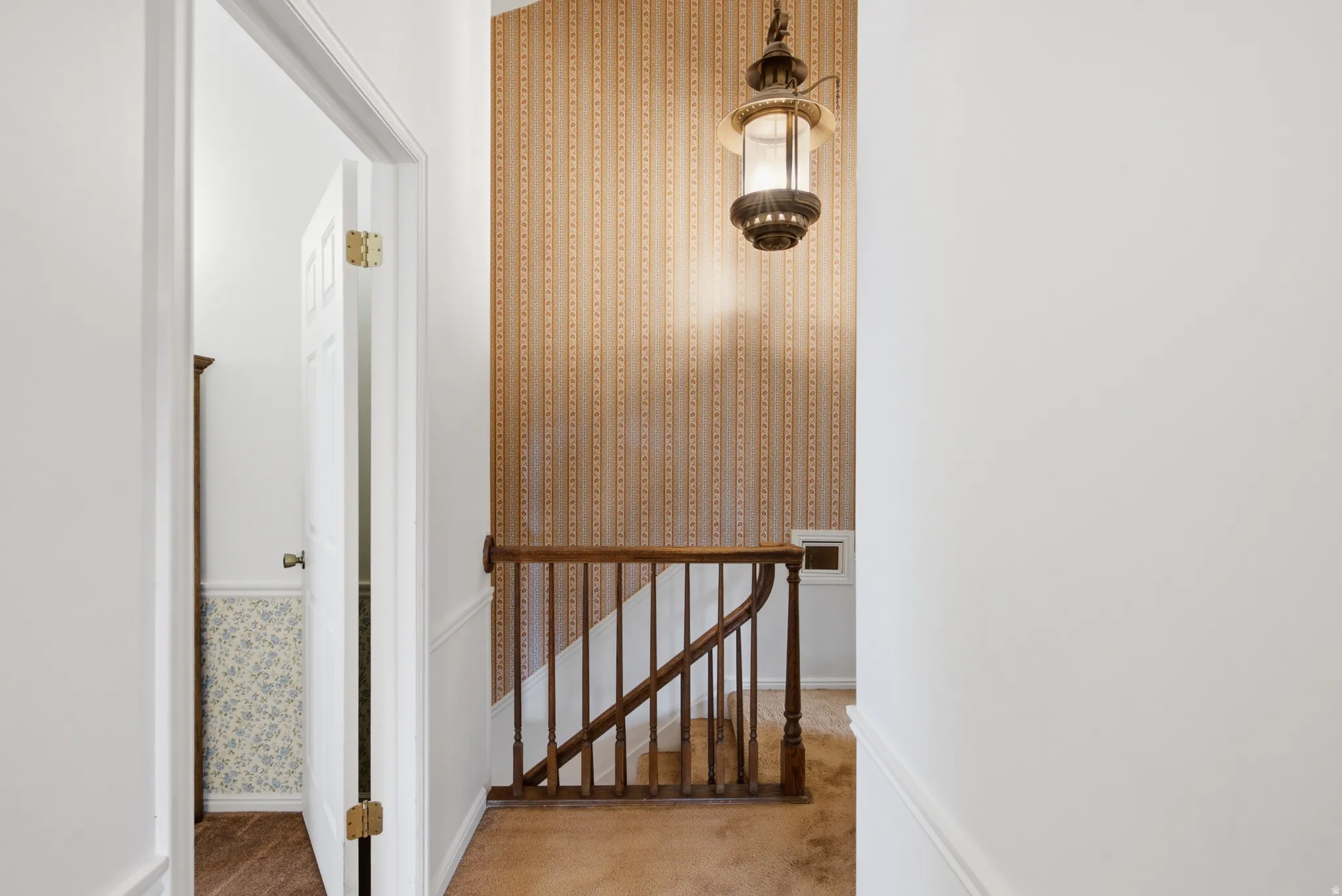 Staircase with wood balusters and a lantern-style pendant light fixture