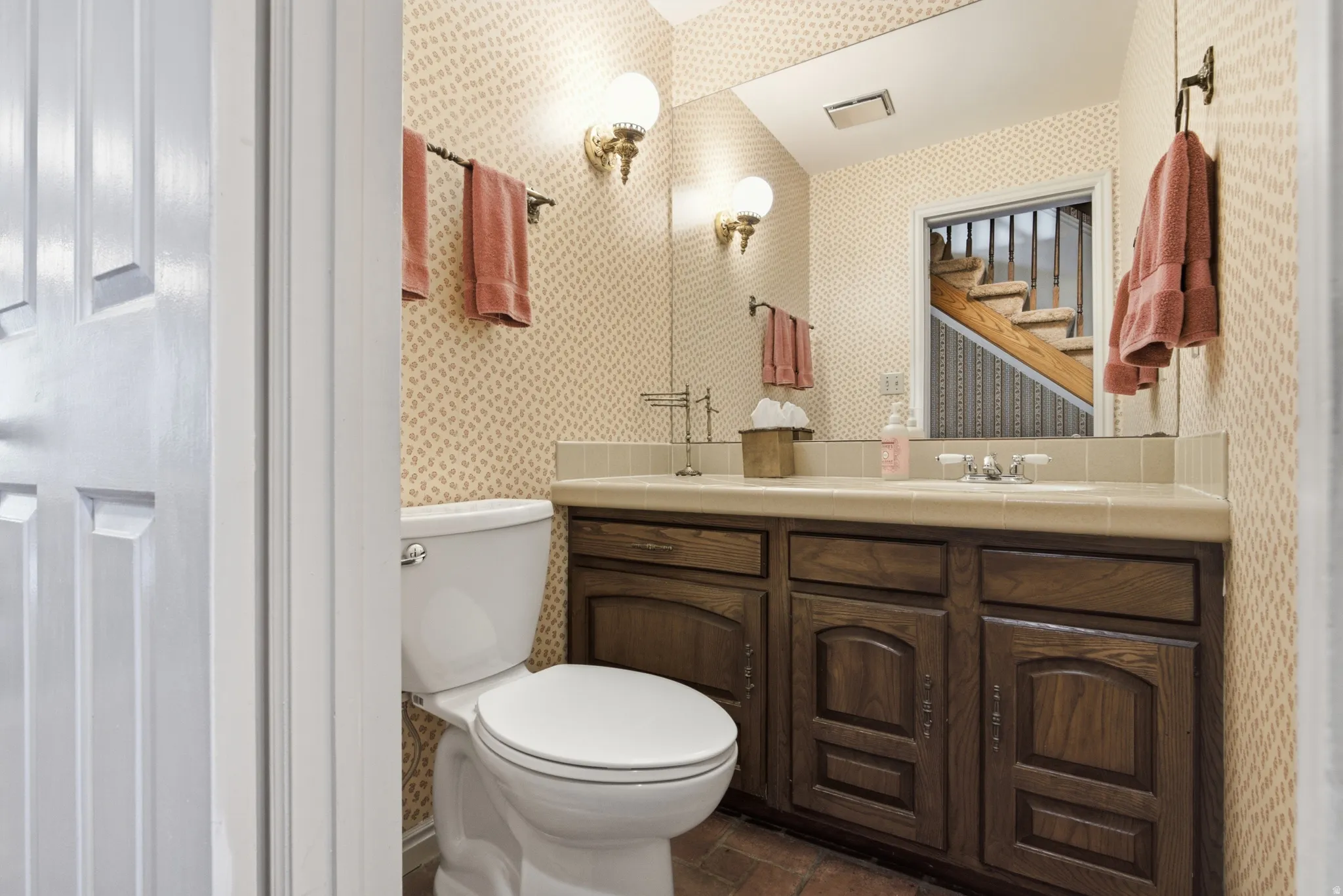 Powder room featuring a single vanity with a solid surface countertop, integrated sink, and an expansive mirror