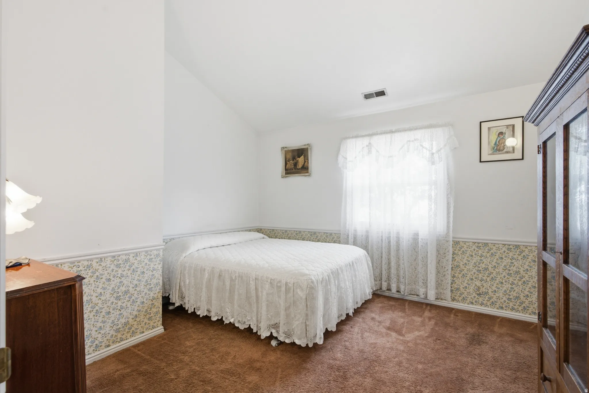 Vaulted ceiling bedroom with white walls and floral wallpaper border