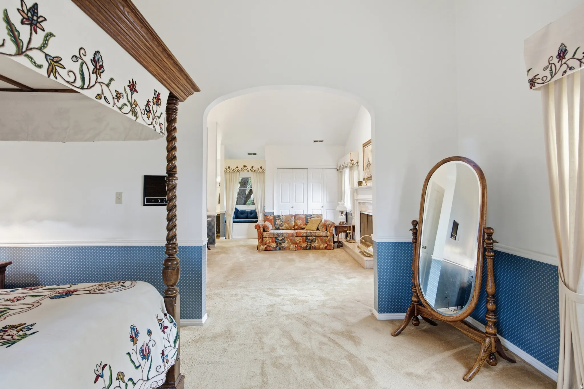 Arched doorway leading to a carpeted room with a fireplace and window seating