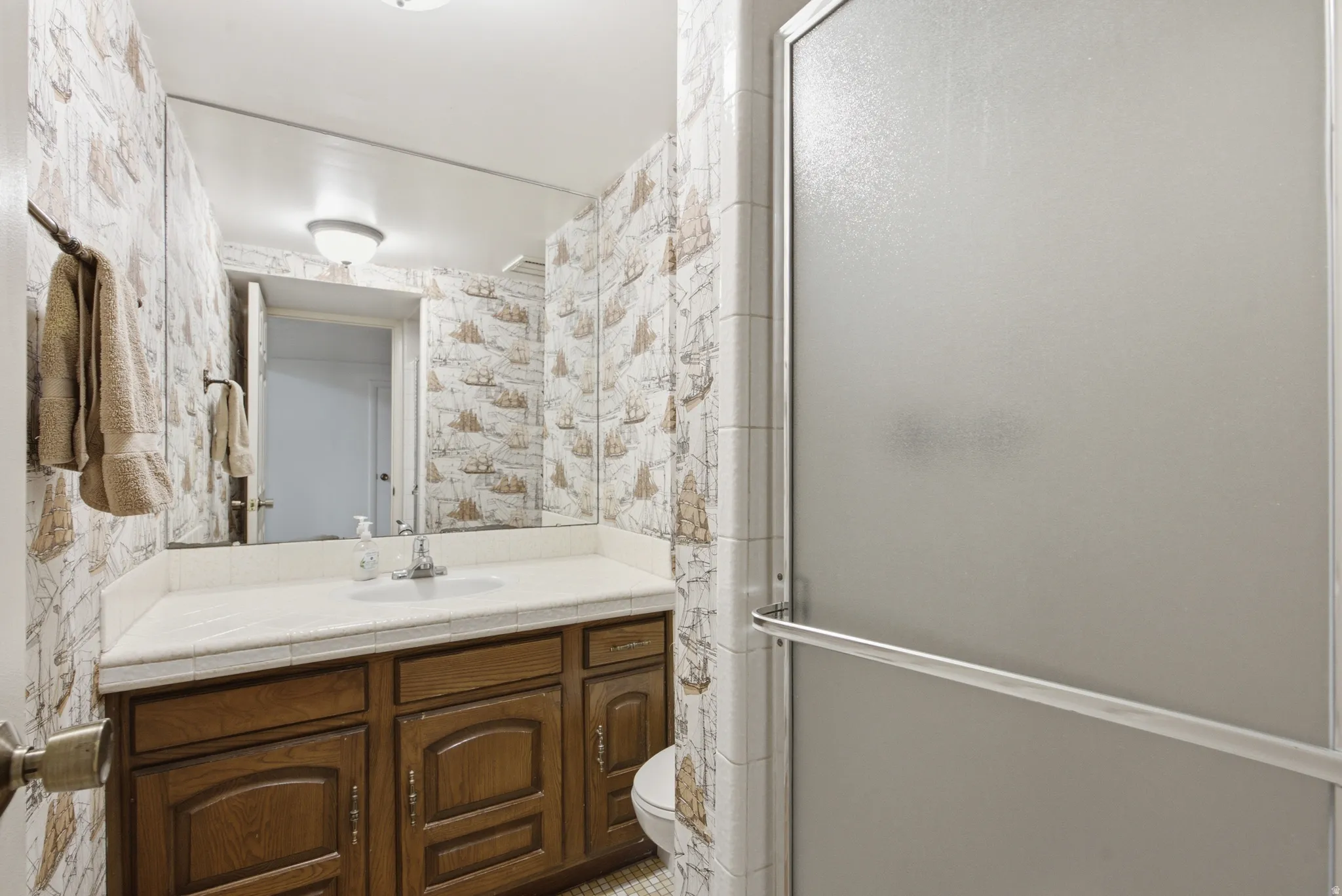 Full bathroom featuring a single vanity with wood cabinetry, a white countertop, and an integrated sink