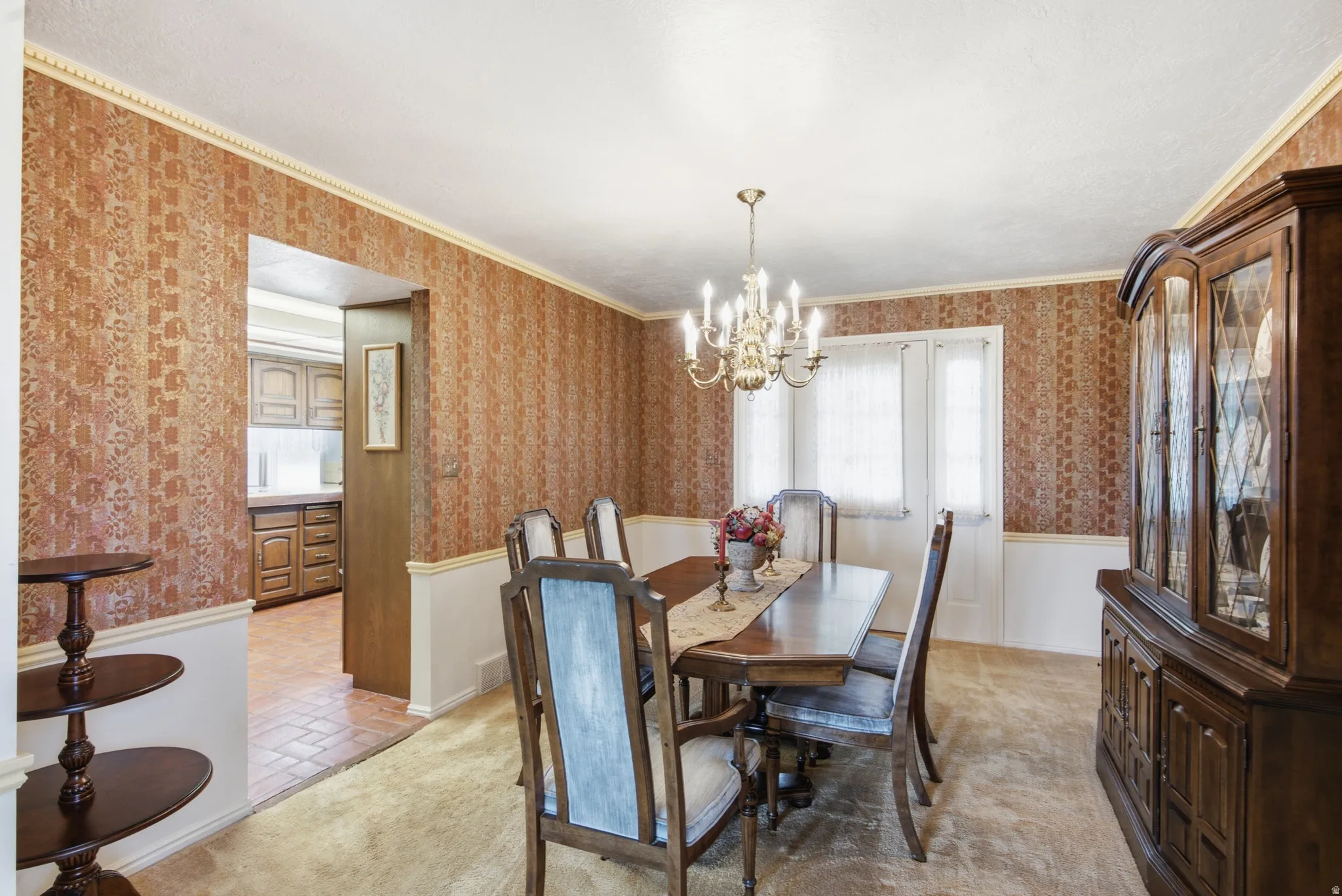 Formal dining area featuring patterned wallpaper, chair rail molding, and a brass chandelier