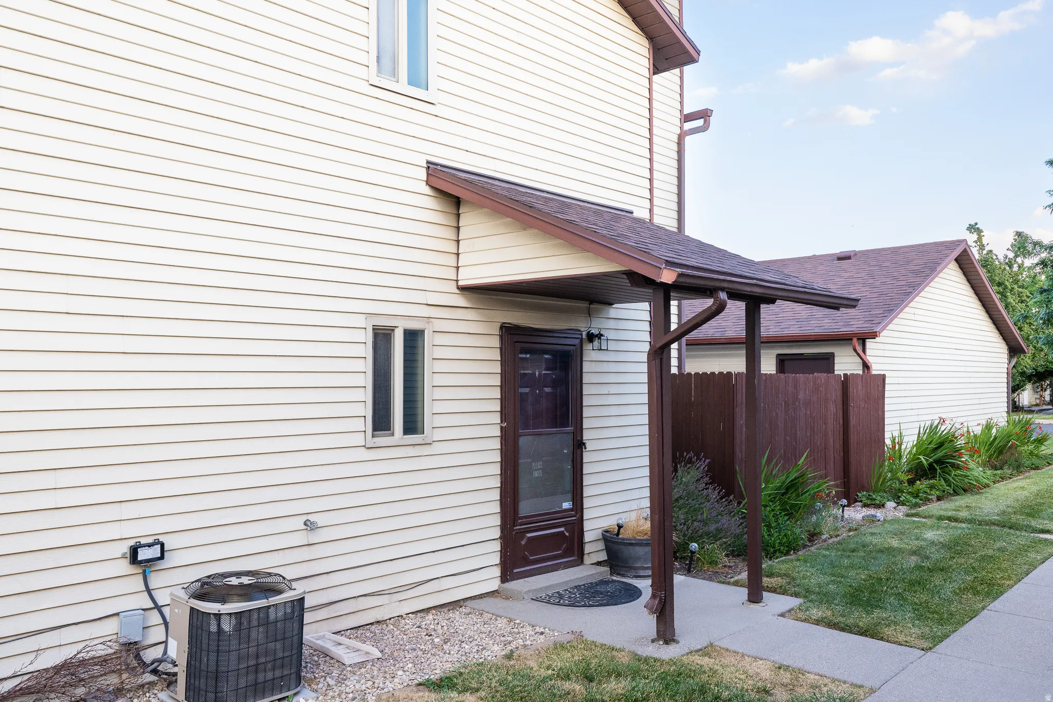 Entryway featuring a brown door with a storm door, sheltered by a matching brown awning