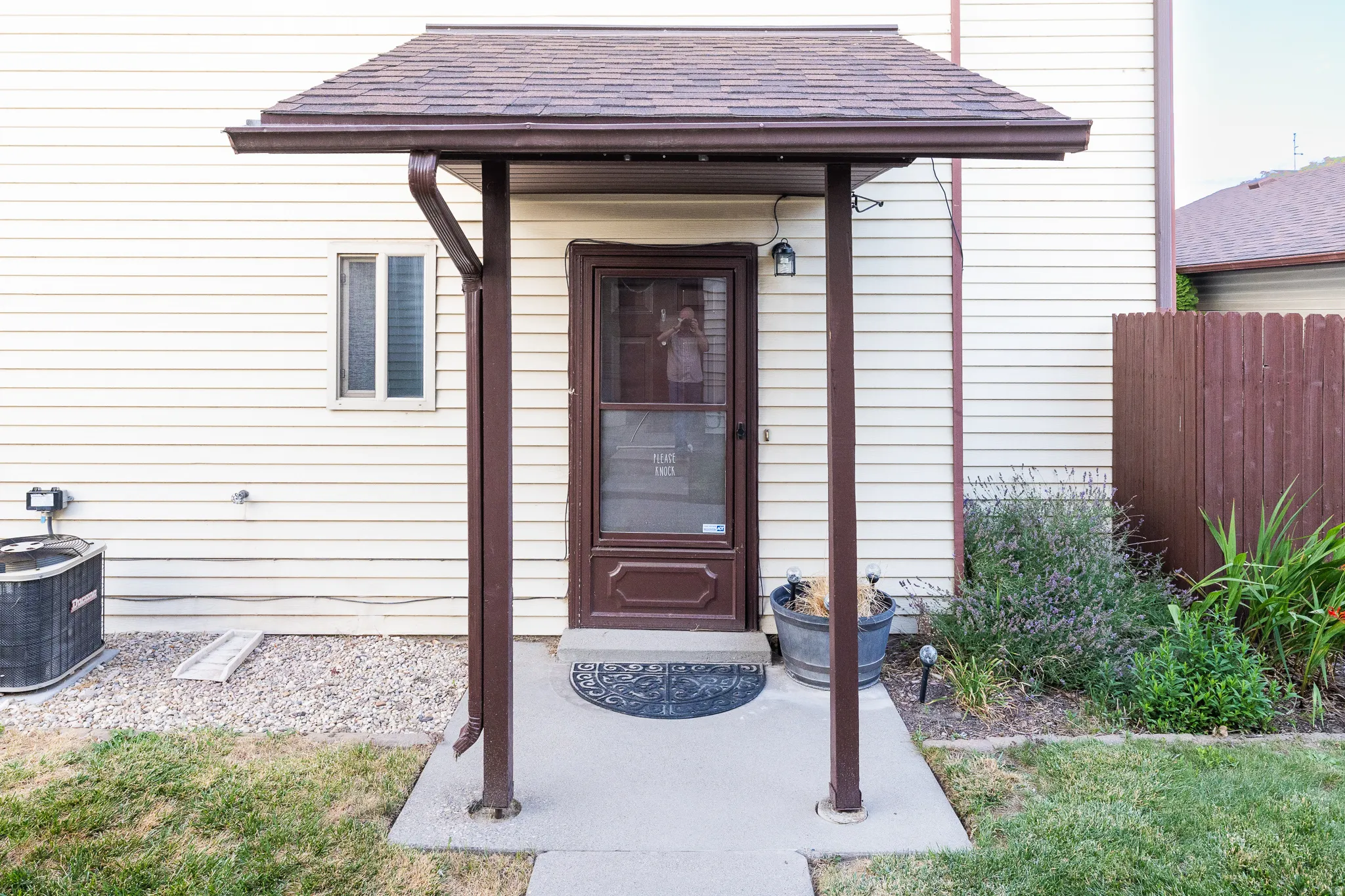 Covered entry with asphalt shingle roof and brown gutter system