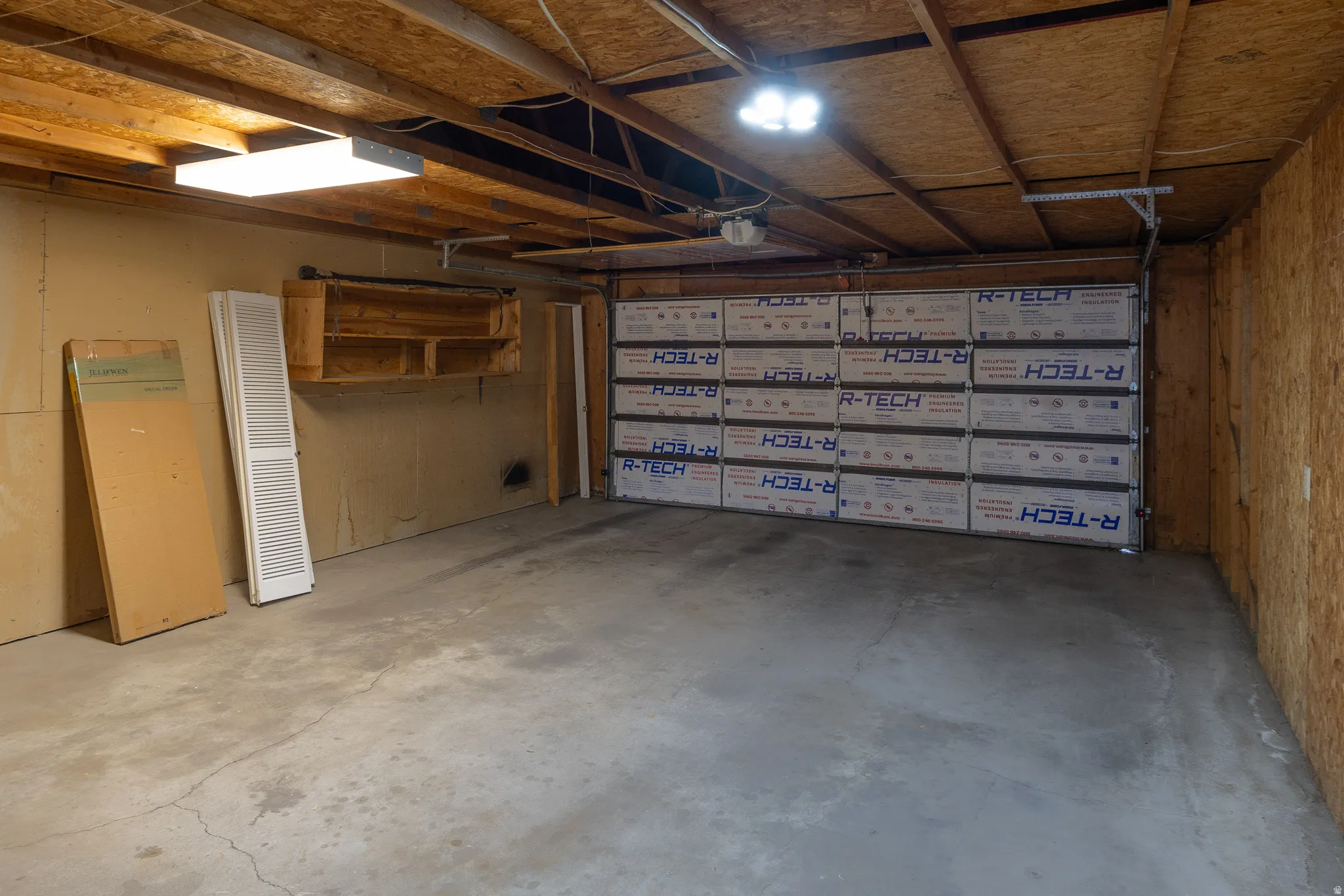 Spacious garage with concrete flooring, exposed wood beam ceiling, and overhead lighting