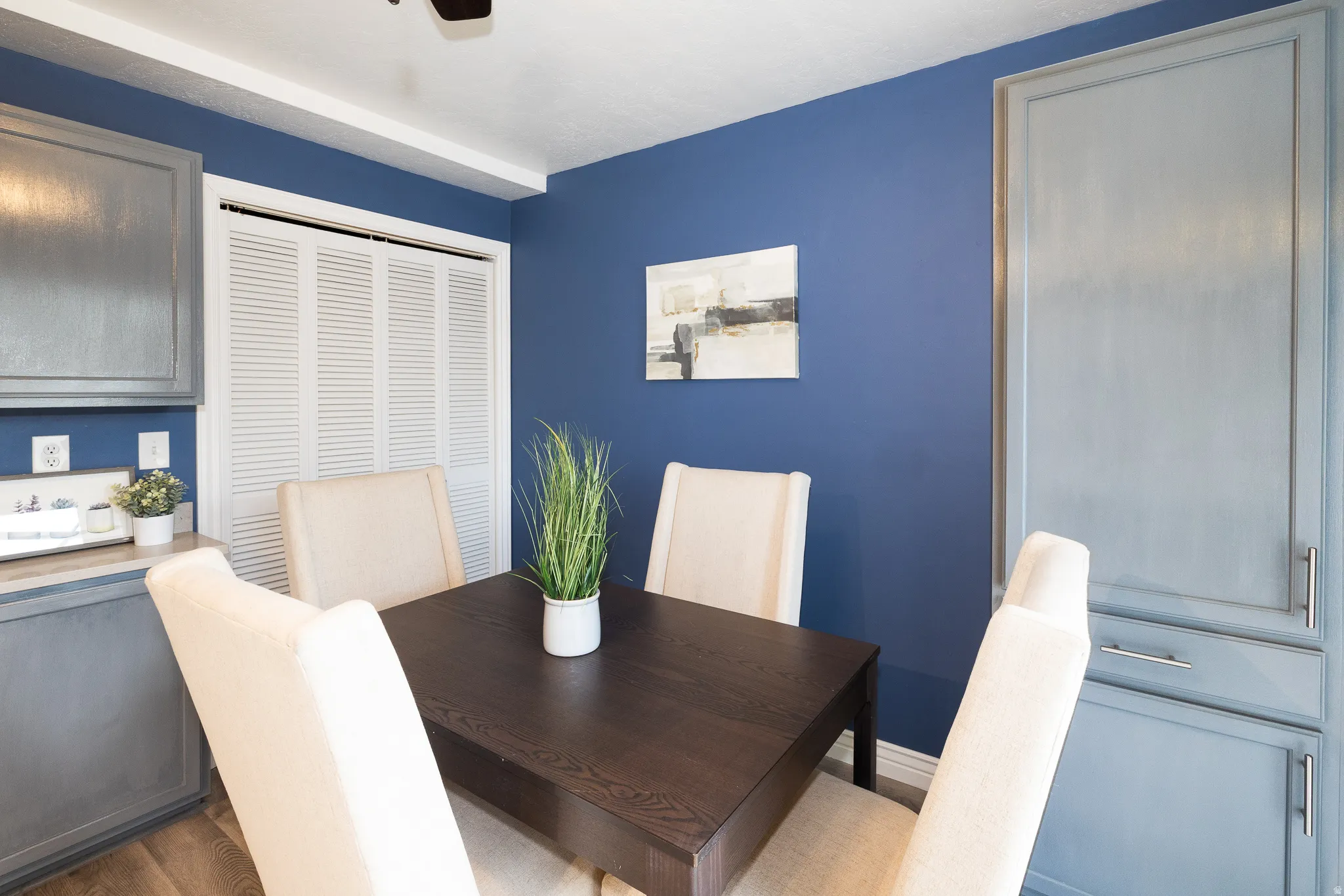 Dining area featuring rich blue walls, wood-finish flooring, and a ceiling fan