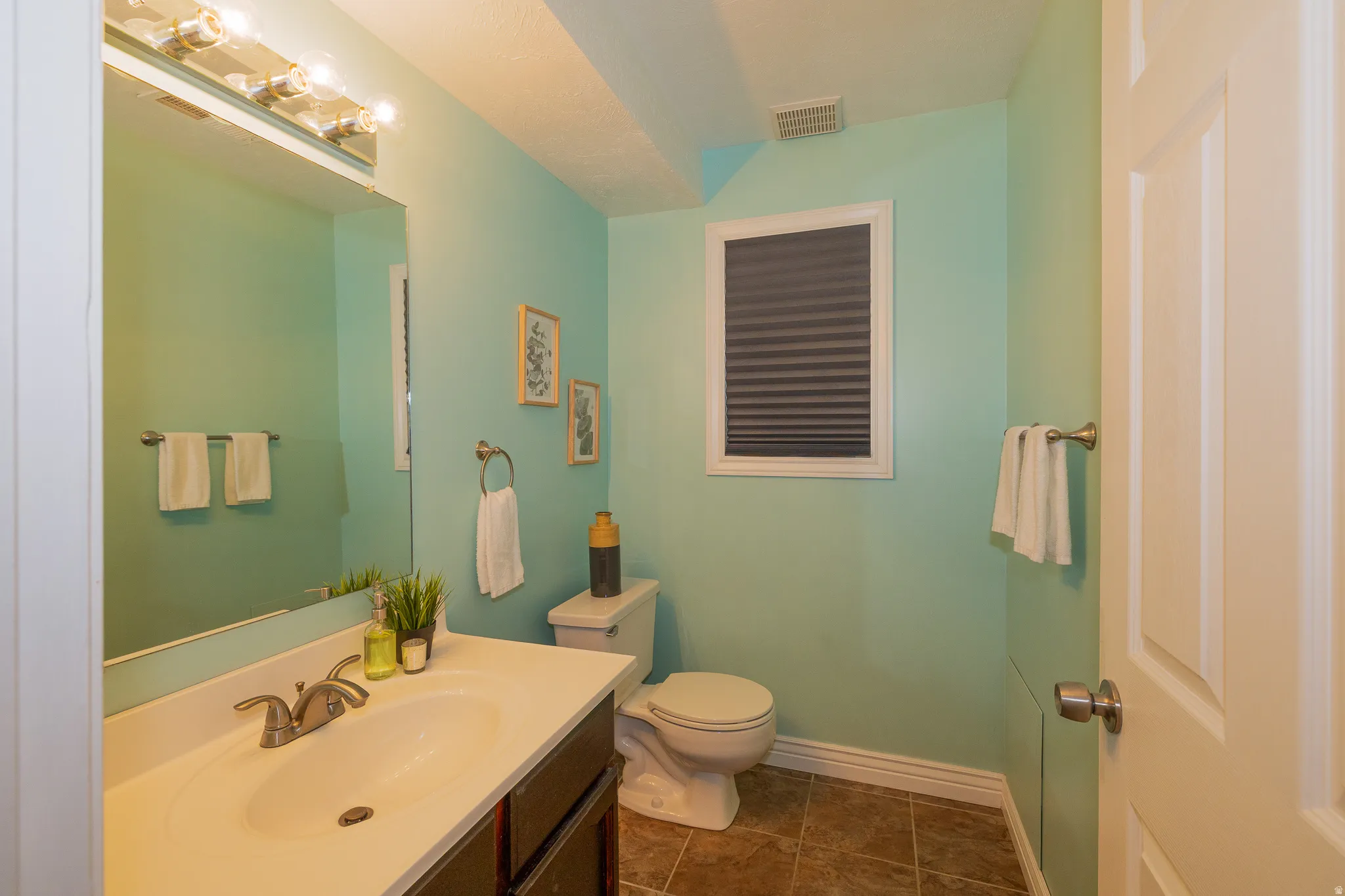 Bathroom featuring a single vanity with an integrated sink, brushed nickel faucet, large wall mirror, and a multi-bulb light fixture