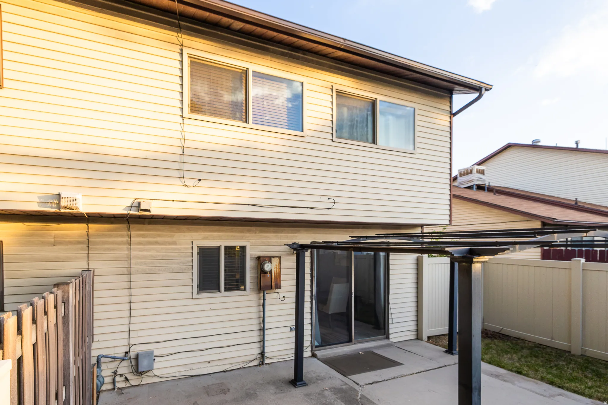 Rear exterior featuring horizontal siding, a sliding glass door, a patio area, and an overhead trellis structure