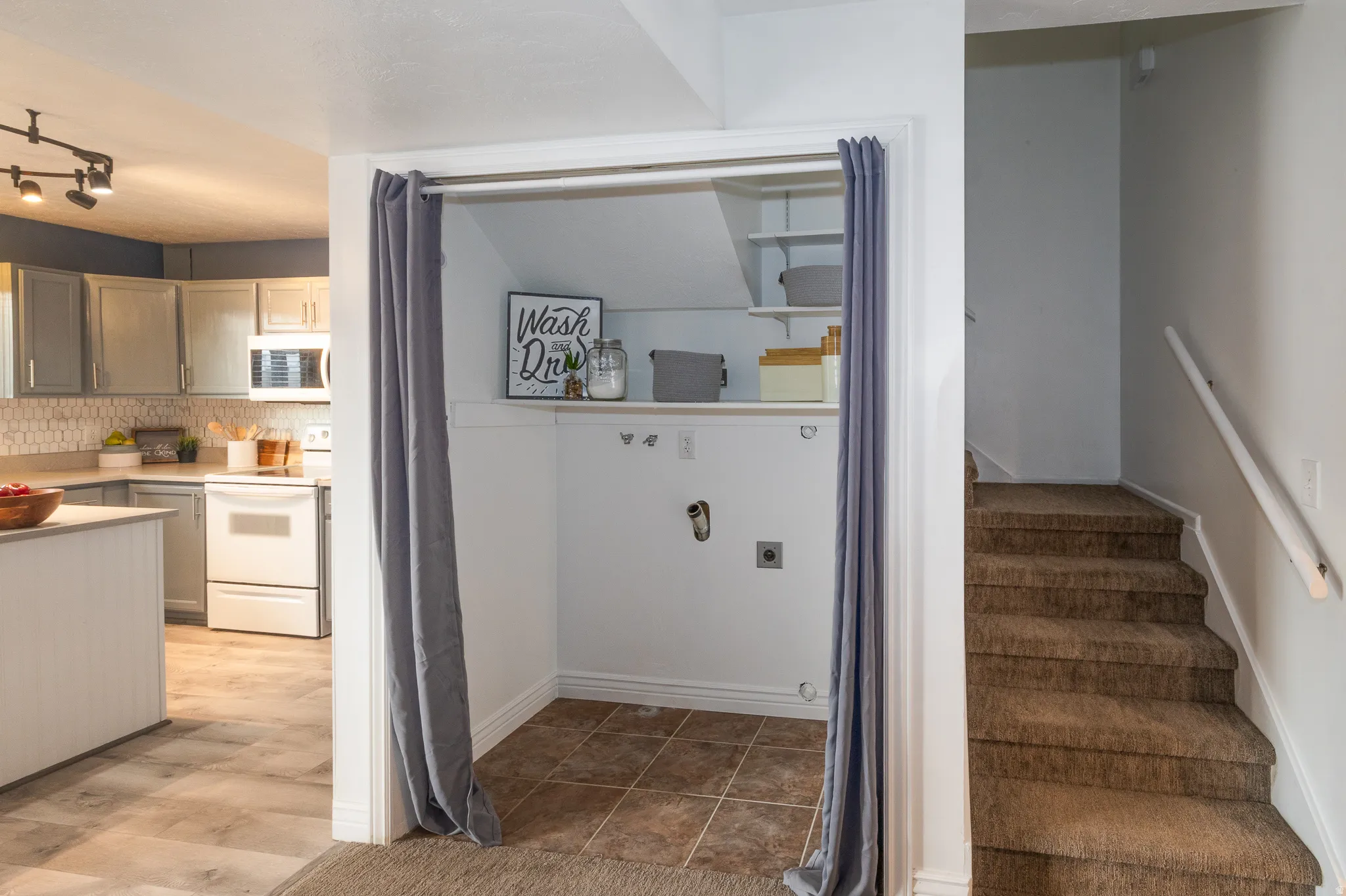 Dedicated laundry nook featuring tile flooring and integrated shelving