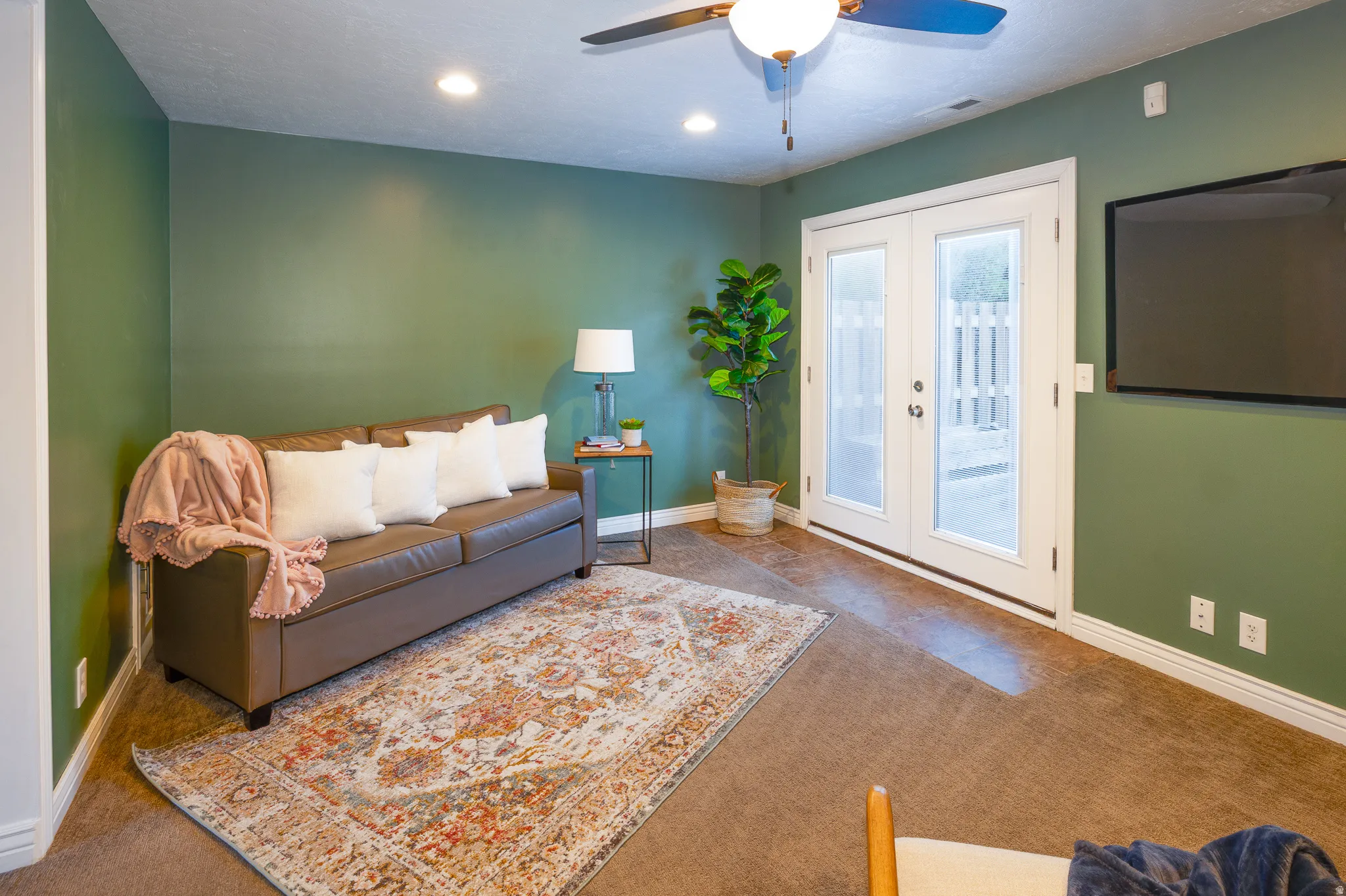 Carpeted room featuring a ceiling fan with integrated lighting, recessed lighting, and a wall-mounted television