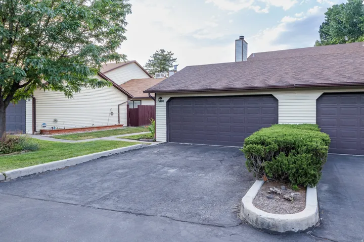 Exterior featuring dual brown garage doors, horizontal cream siding, and a brown shingle roof