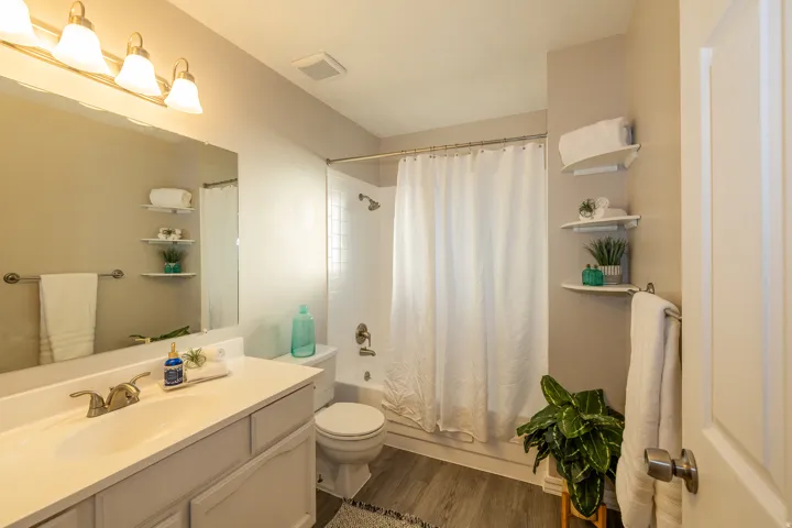 Bathroom featuring a light-colored vanity with an integrated sink, brushed nickel faucet, a large wall-mounted mirror, and a three-bulb vanity light fixture