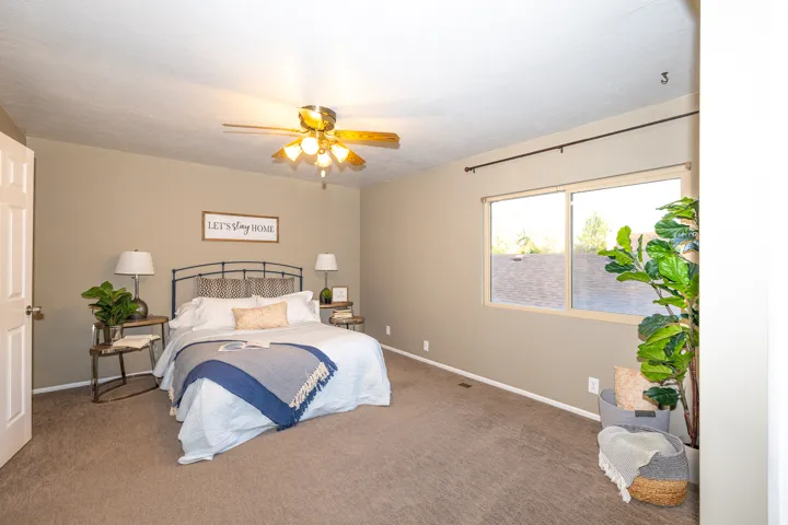 Carpeted room featuring a ceiling fan, dual windows with a dark rod, and neutral wall paint