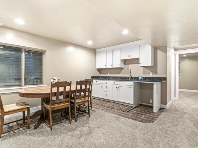 Lower-level entertainment space featuring a wet bar with white cabinetry and dark countertops