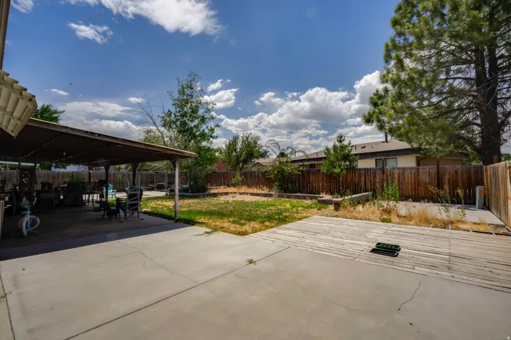 Expansive backyard featuring a covered patio, a concrete slab, and a wooden deck