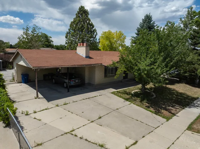 Ranch-style residence featuring a carport, a brick chimney, and a brown shingle roof