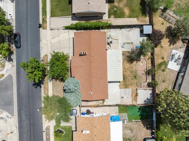 Overhead property view featuring a brown shingle roof, mature landscaping, and a concrete driveway