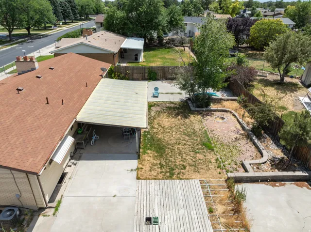 Spacious backyard featuring a concrete patio, wood deck area, and a covered carport