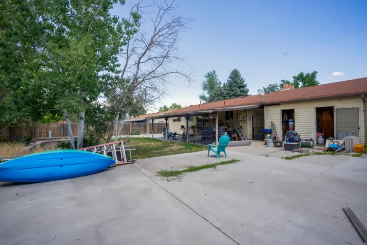 Expansive concrete patio area with a covered porch and mature trees