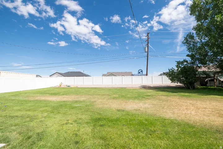 Expansive green lawn fully enclosed by a white privacy fence