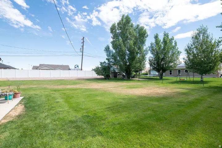 Expansive green lawn with mature trees and a white privacy fence