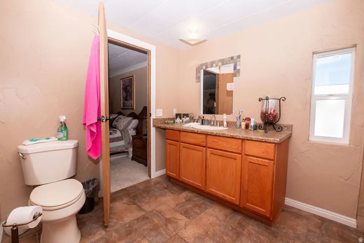 Bathroom featuring a wood-finish vanity with a built-in sink, a framed mirror, and a window for natural light