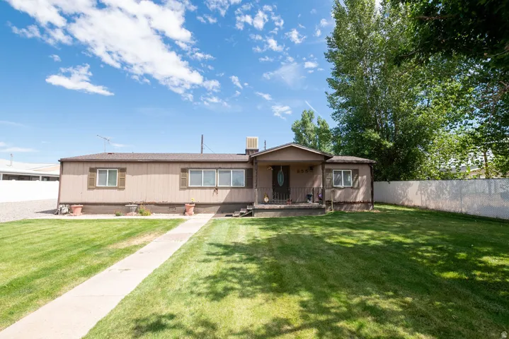 Expansive front lawn with a concrete pathway to the covered entry