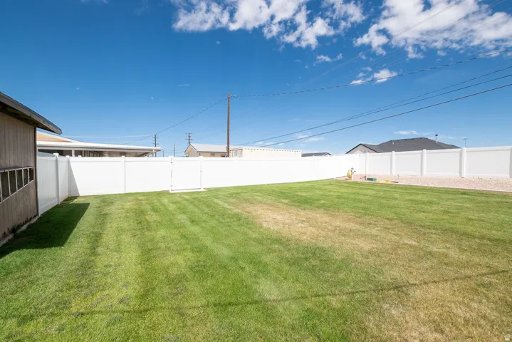 Spacious backyard featuring a manicured lawn, full privacy fencing, and a gravel border