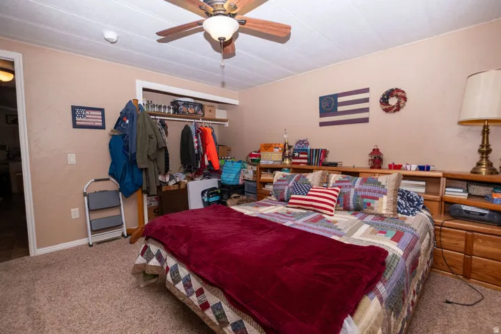 Bedroom featuring a ceiling fan with light fixture, textured beige walls, and carpet flooring