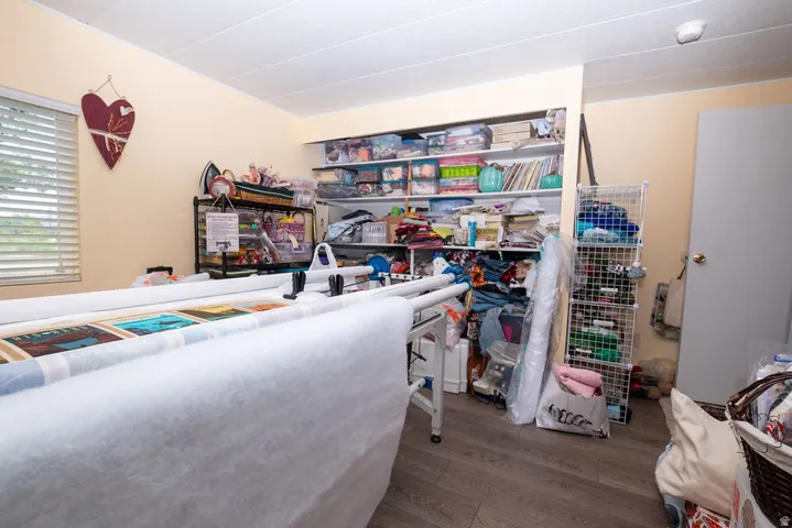 Room featuring wood-finish flooring, built-in shelving, and a neutral wall color