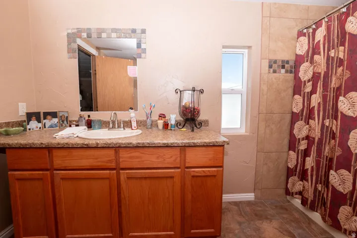 Bathroom featuring a wood-finish vanity with a built-in sink and speckled countertop