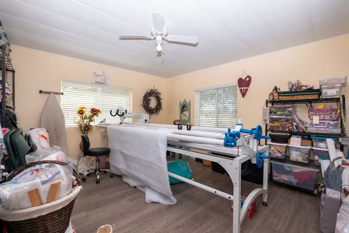 Spacious room featuring light-colored walls, wood-finish flooring, and multiple windows with blinds