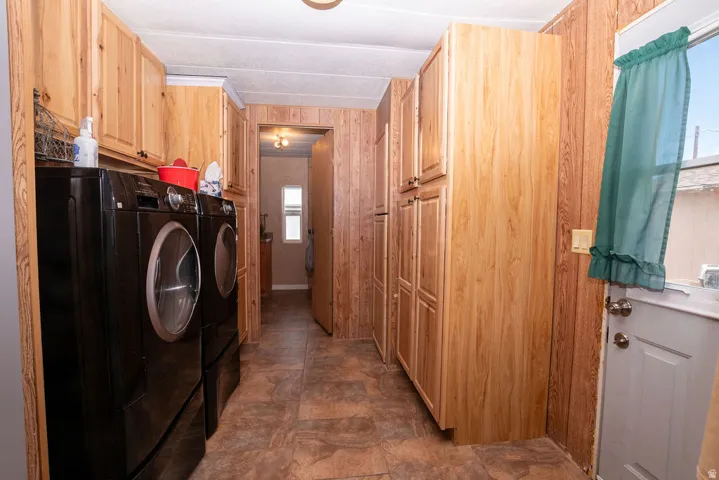 Utility room featuring wood-finish wall paneling, ceiling-mounted light fixture, and wood-finish cabinetry providing ample storage