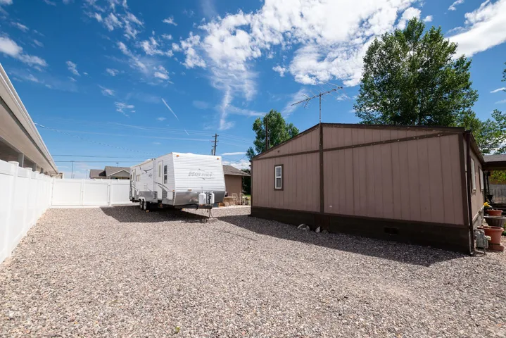 Expansive gravel area providing ample off-street parking, enclosed by a white privacy fence, offering space for recreational vehicles