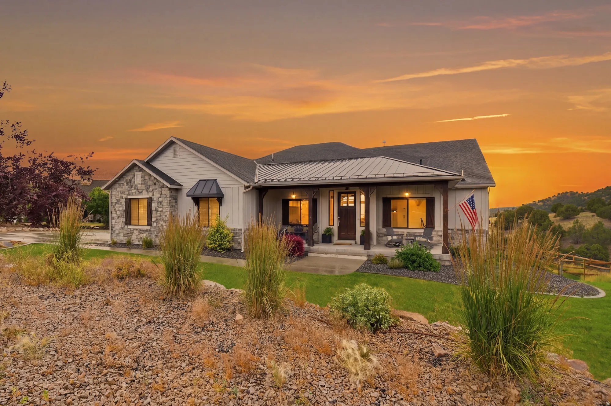 Contemporary ranch-style residence featuring a stone and siding exterior, covered porch, dark entry door, and a metal roof accent