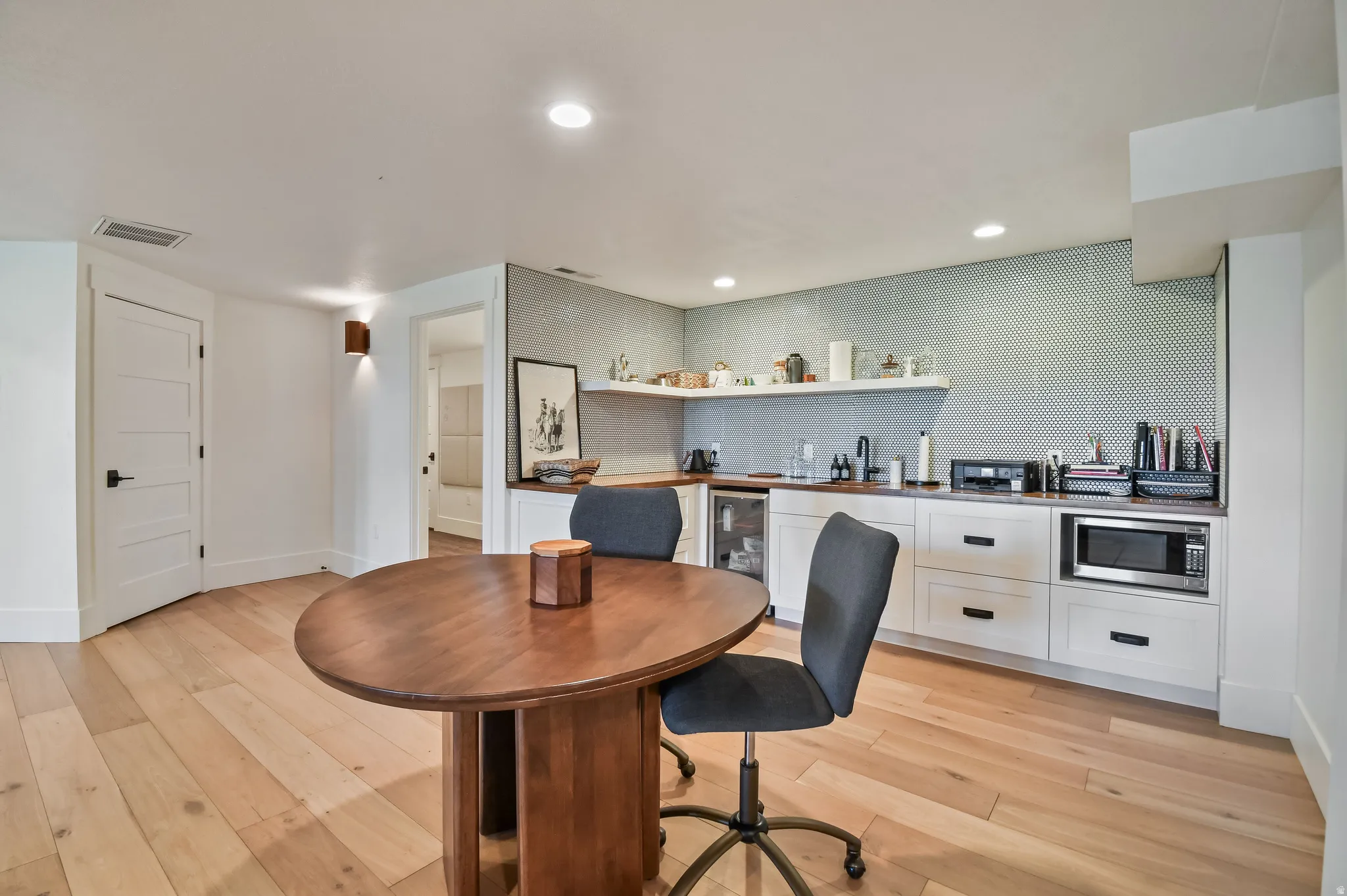 Kitchenette room featuring wood-finish flooring, a built-in wet bar with white cabinetry, open shelving, and a patterned tile backsplash
