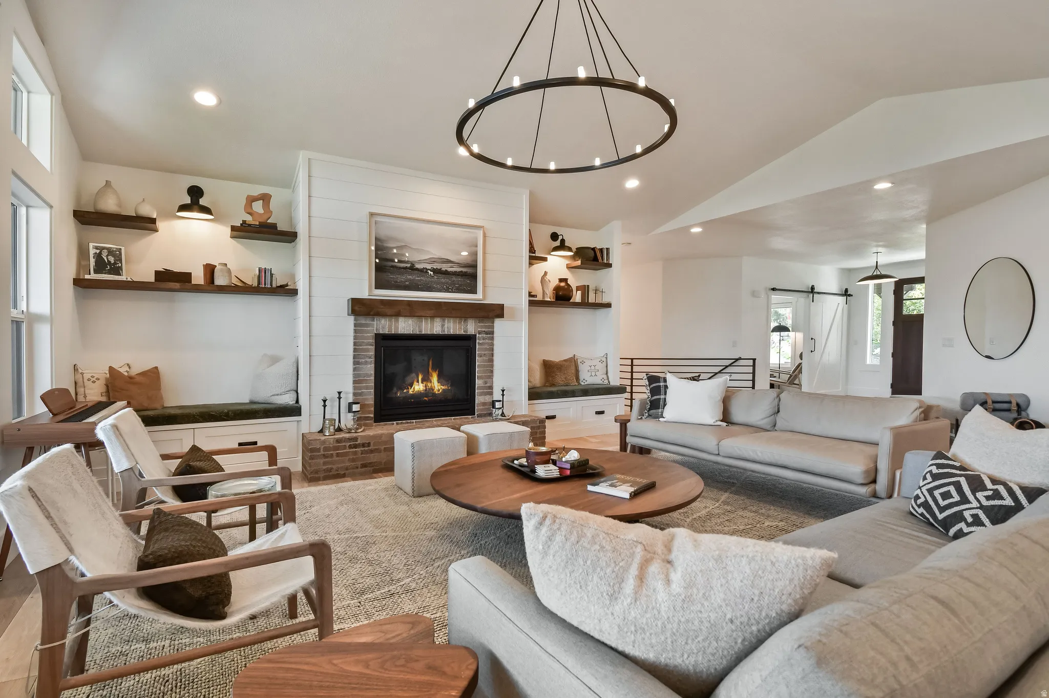 Spacious living area featuring a brick fireplace with wood mantle, built-in bench seating with storage, and integrated shelving