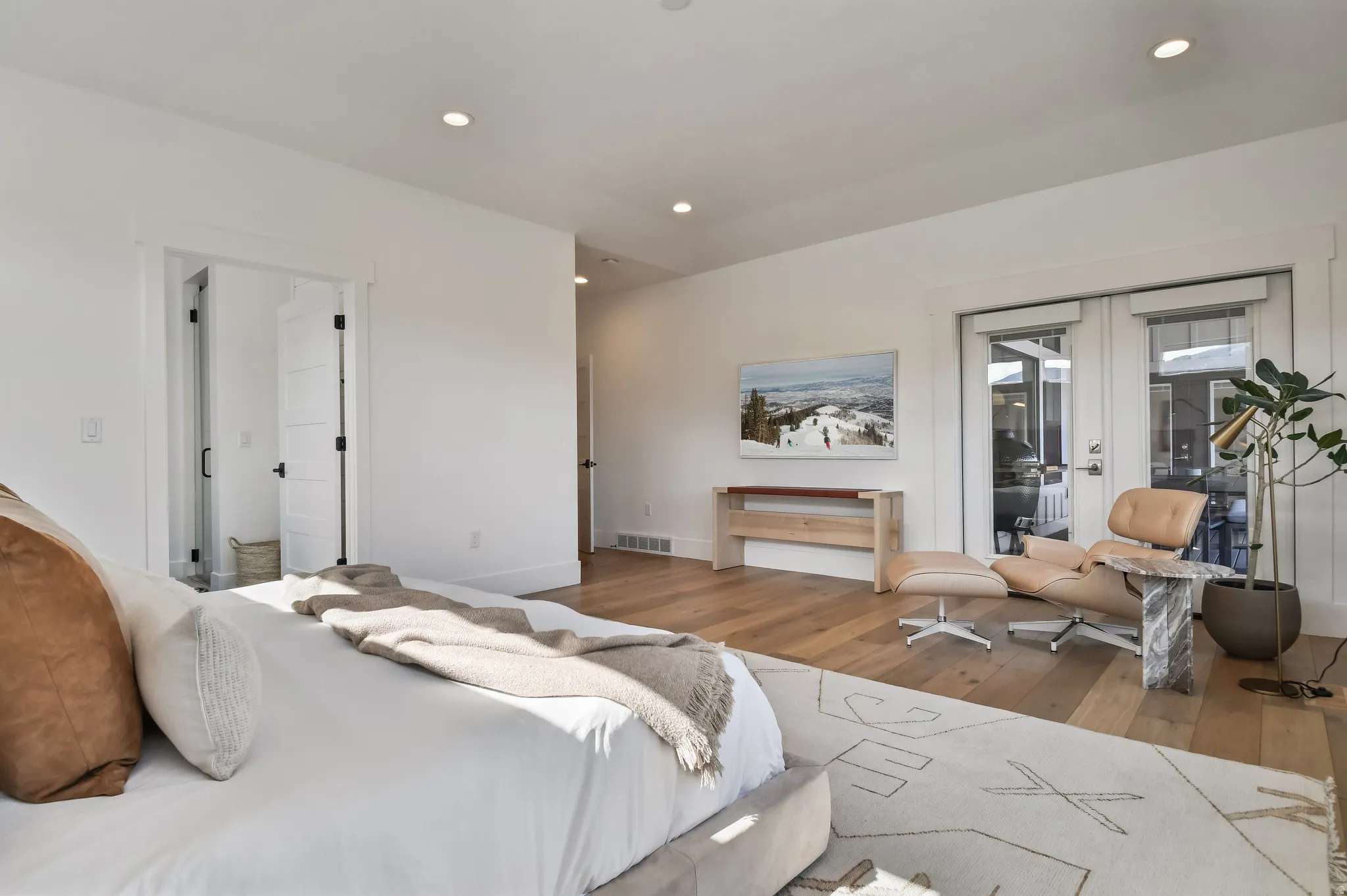 Primary Bedroom hardwood flooring with recessed lighting, bright white walls, and French doors leading to exterior