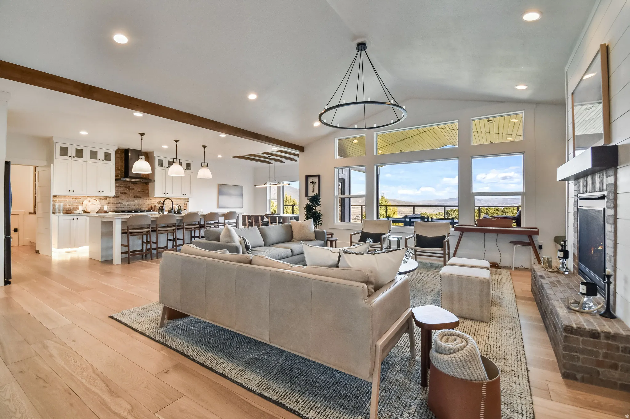 Open-concept living area featuring light wood-finish flooring and vaulted ceilings with exposed wood beams