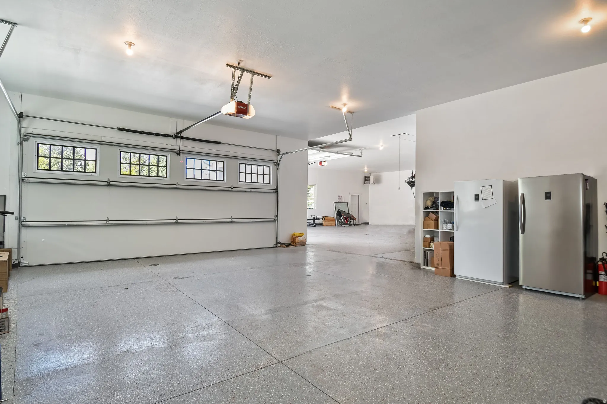 Spacious garage featuring a light gray epoxy floor finish and a white sectional overhead door with upper window panels