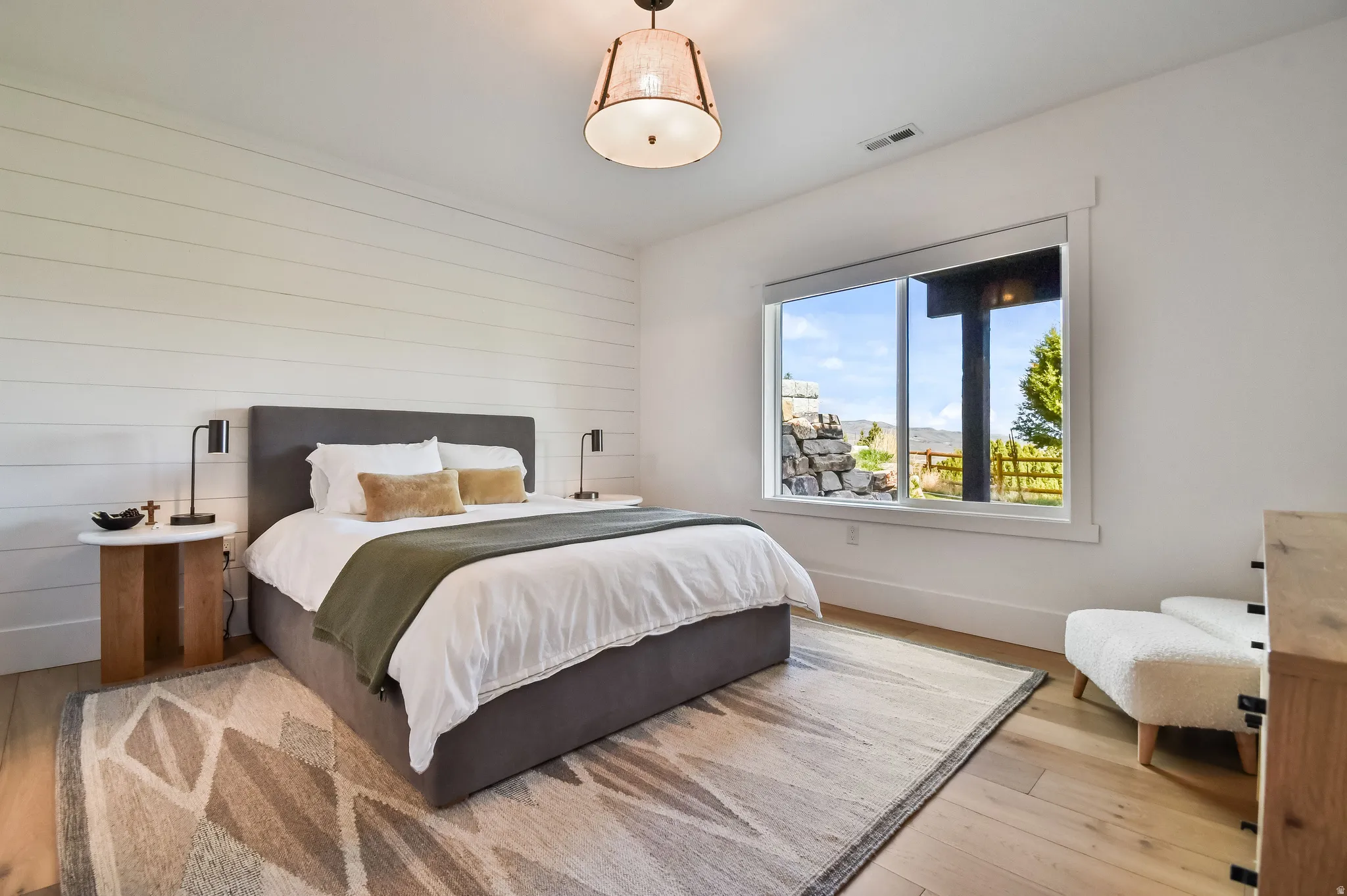 Bedroom featuring a shiplap accent wall, light wood-finish flooring, and a large window