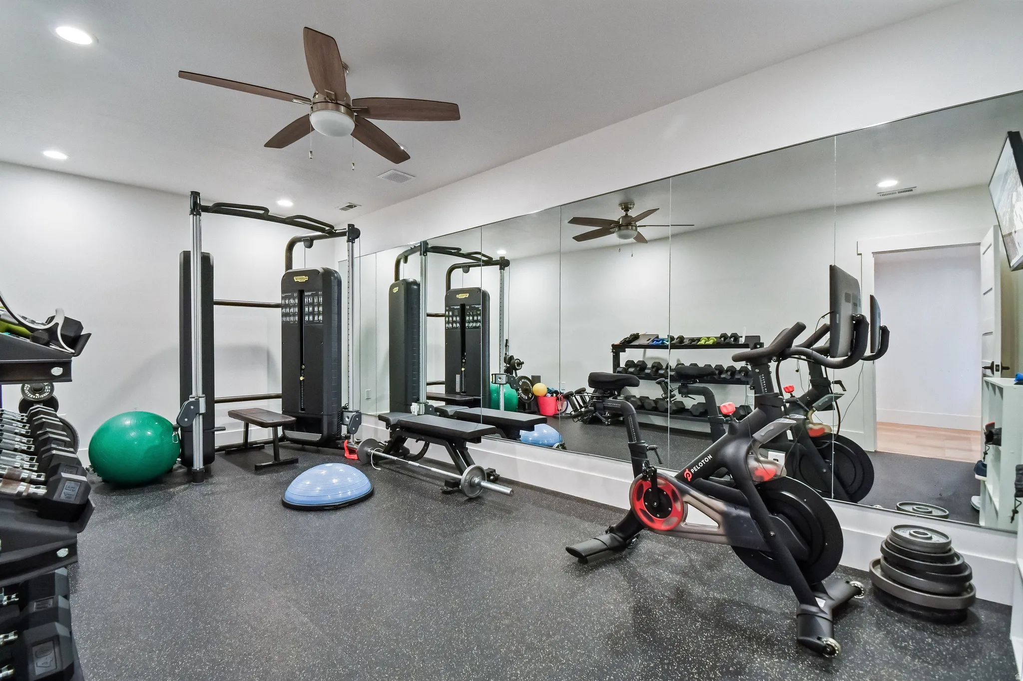 Dedicated fitness space featuring rubber flooring, a full wall of mirrors, and recessed lighting