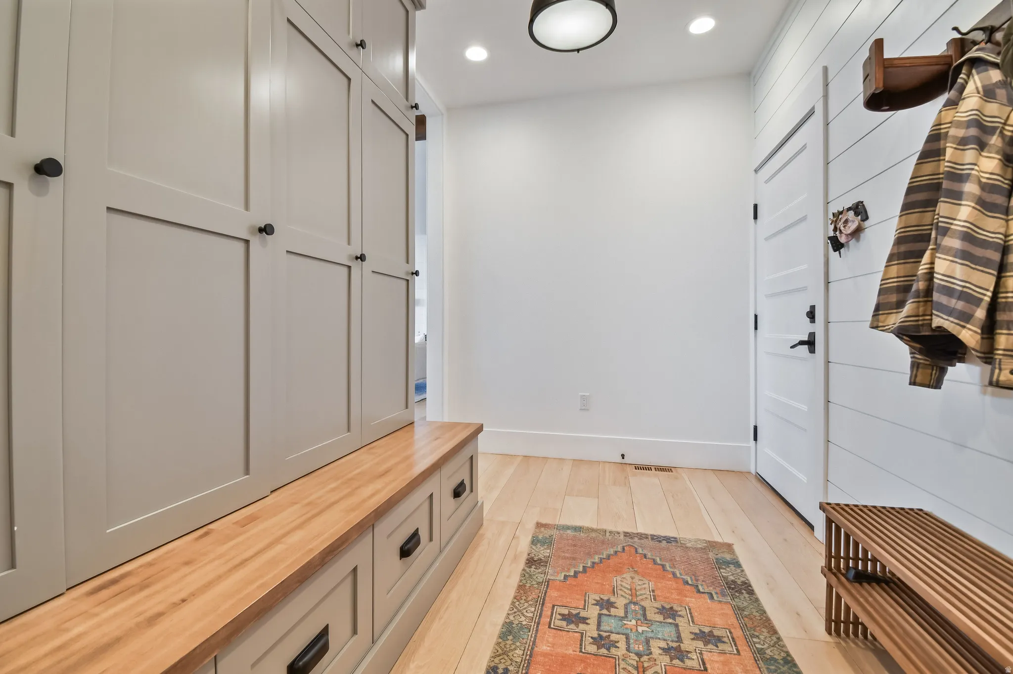 Mud Room featuring light wood-finish flooring, recessed lighting, and a built-in storage system with a wood-top bench and integrated drawers