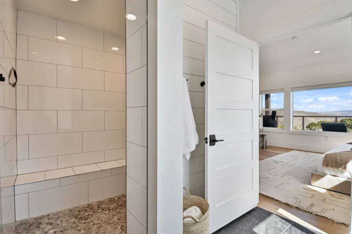 Primary bathroom with walk-in shower with white subway tile walls, a built-in bench, and a pebble-finish floor