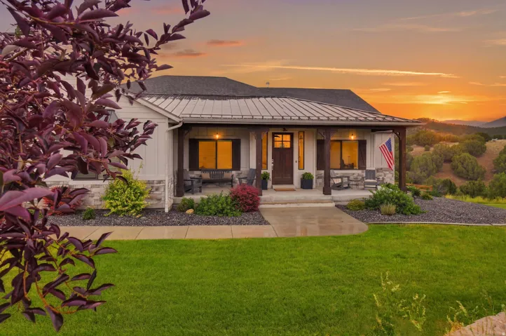 Ranch-style exterior featuring a covered front porch with wood-wrapped posts, a metal roof accent, and board-and-batten siding