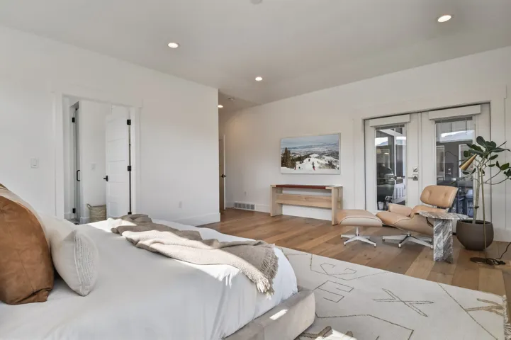 Primary Bedroom hardwood flooring with recessed lighting, bright white walls, and French doors leading to exterior