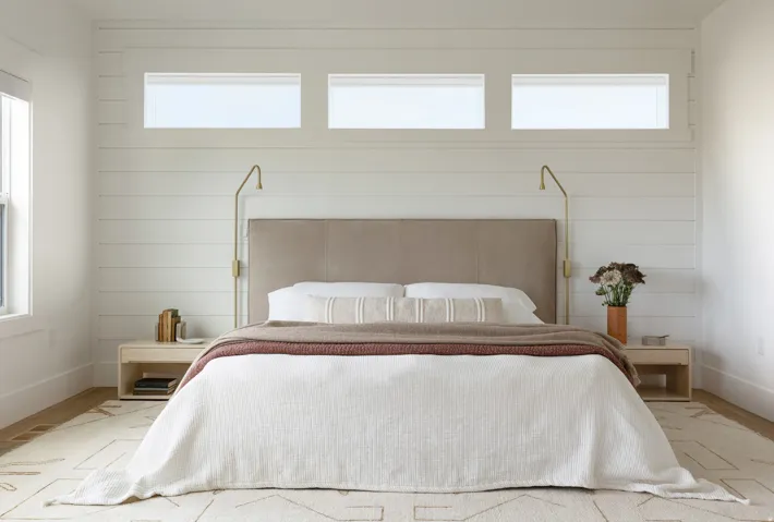 Bedroom featuring shiplap accent wall, built-in wall sconces, three transom windows, and durable wood-finish flooring