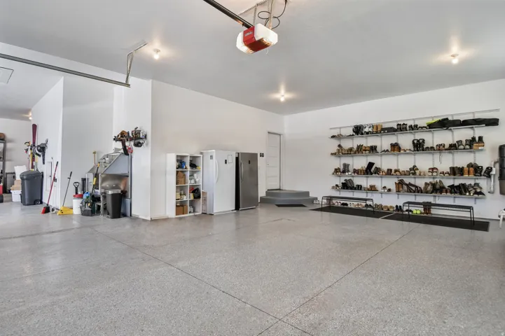 Spacious garage with light gray speckled flooring, white walls, and built-in overhead lighting